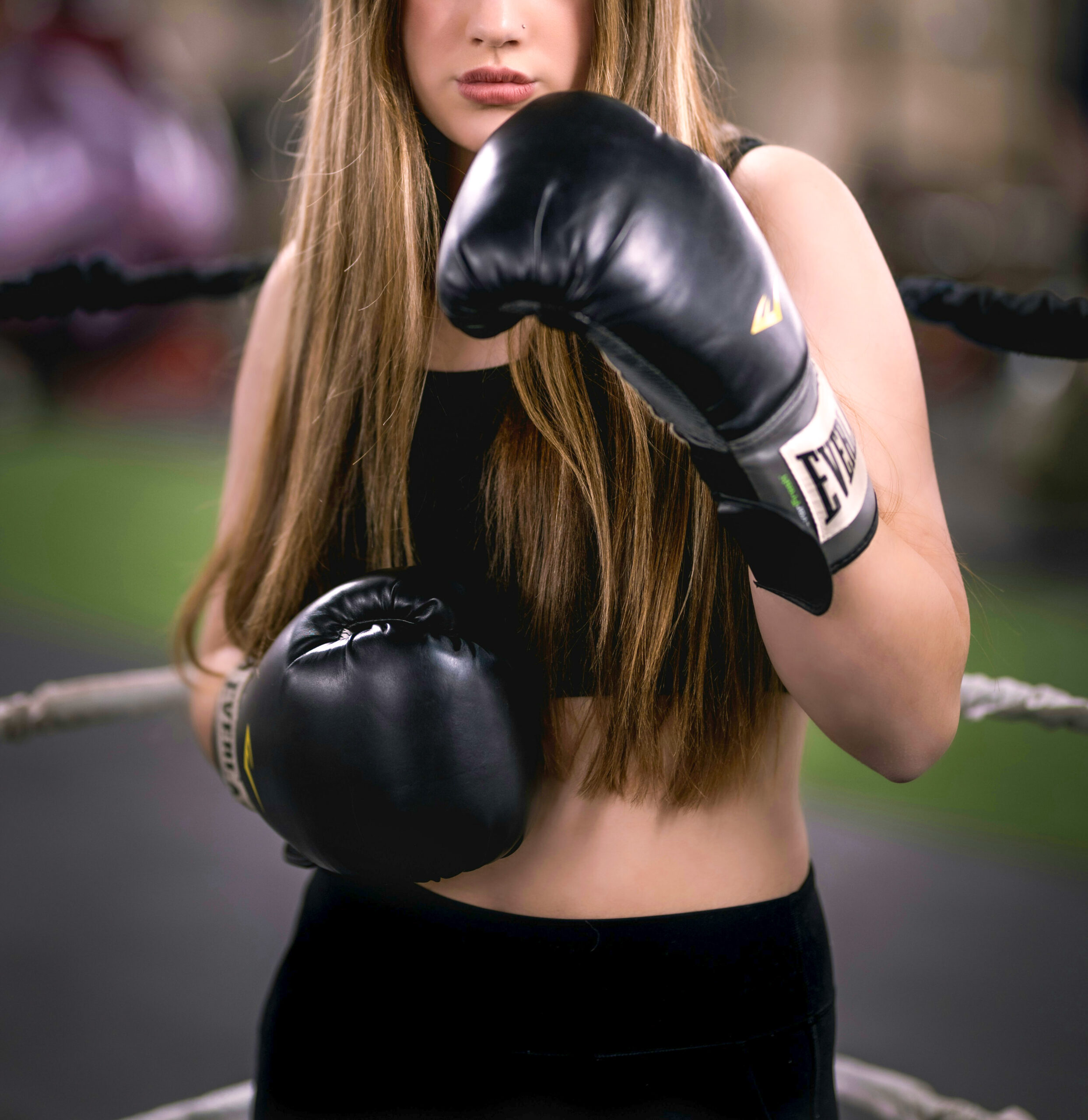 woman wearing boxing gloves poses ring side